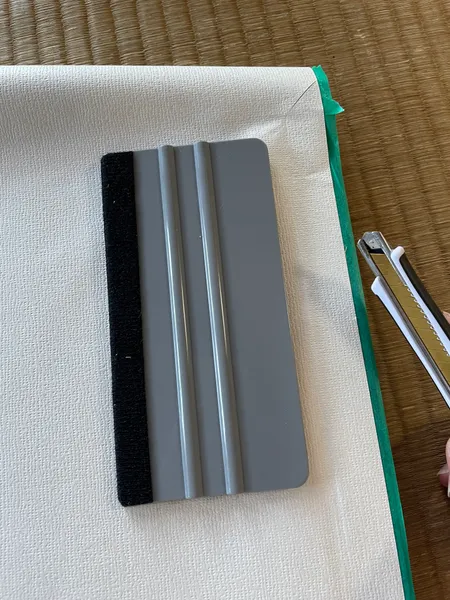 枠に沿ってはみ出したふすま紙を切っているところ