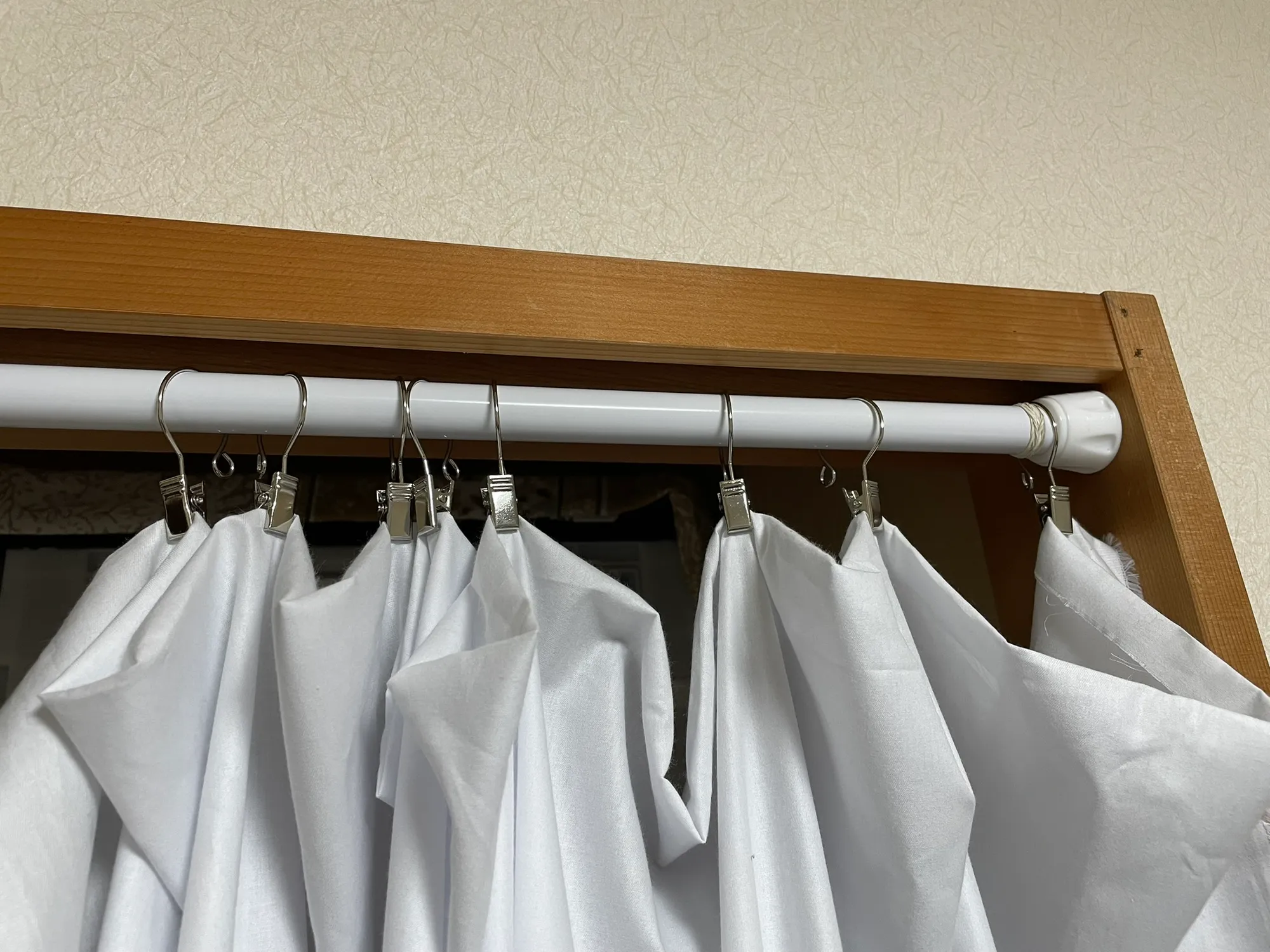 突っ張り棒にカーテンクリップを用いて布を吊るした写真