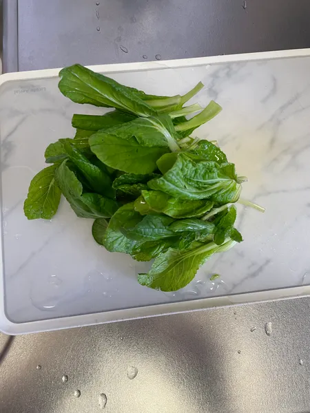 まな板にのせた、根を落としたビタミン菜の葉